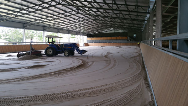 Grader completing ground laser levelling preparation across a large warehouse.